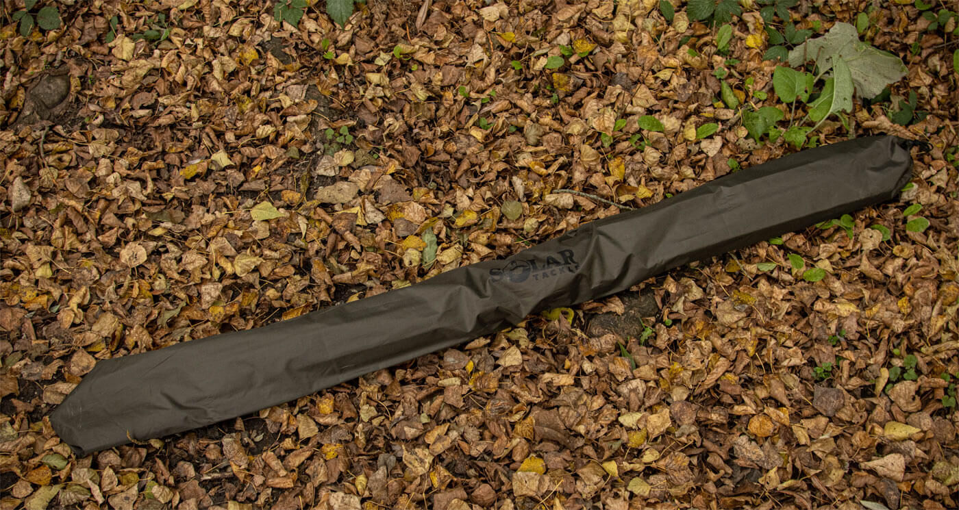 solar-brolly-UG21-5 Odolné pouzdro na prut spočívající na lůžku podzimního listí, ideální pro ochranu rybářských prutů.