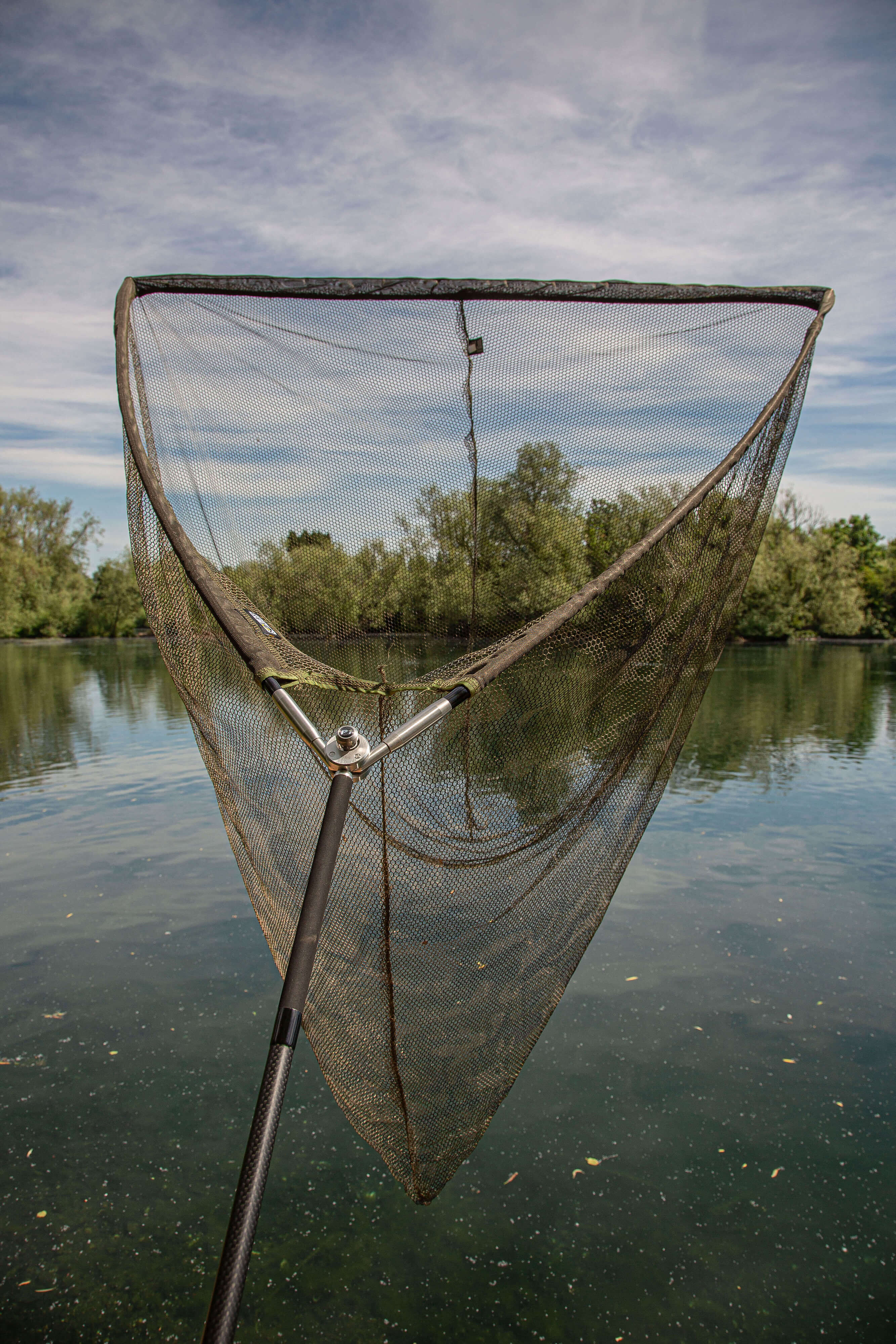 solar-tackle-P1BL42X-bow-loc-upgraded-2 Een visnet klaar om karpers te vangen, dat het serene water en de weelderige omgeving weerspiegelt.