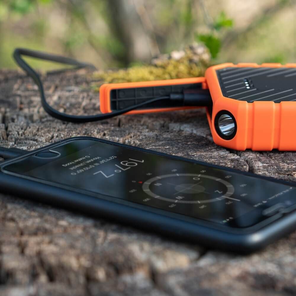 xtorm-xr102-1 Přenosná nabíječka a smartphone na dřevěném povrchu, ideální pro rybářské výlety.