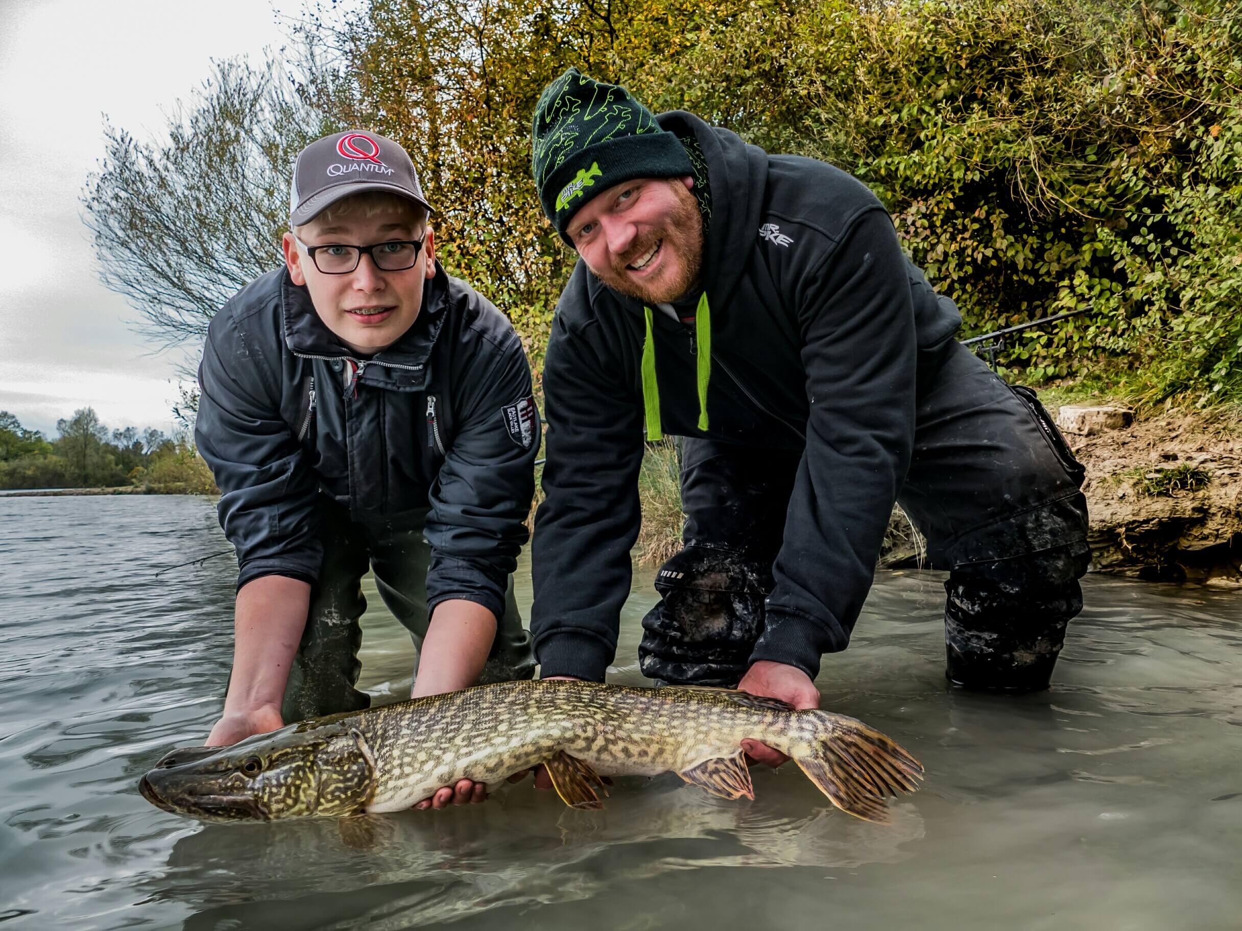 hecht-angelzelt Zwei Angler halten stolz einen großen Hecht in der Hand, der während eines Angelausflugs gefangen wurde.