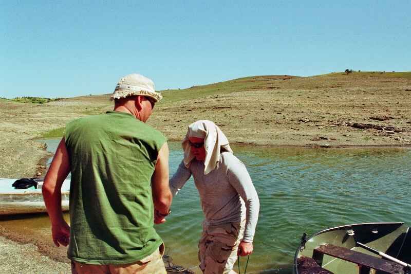 Erkundungstour-2 Zwei Angler bereiten ihr Boot für einen Tag Karpfenangeln am Wasser vor.