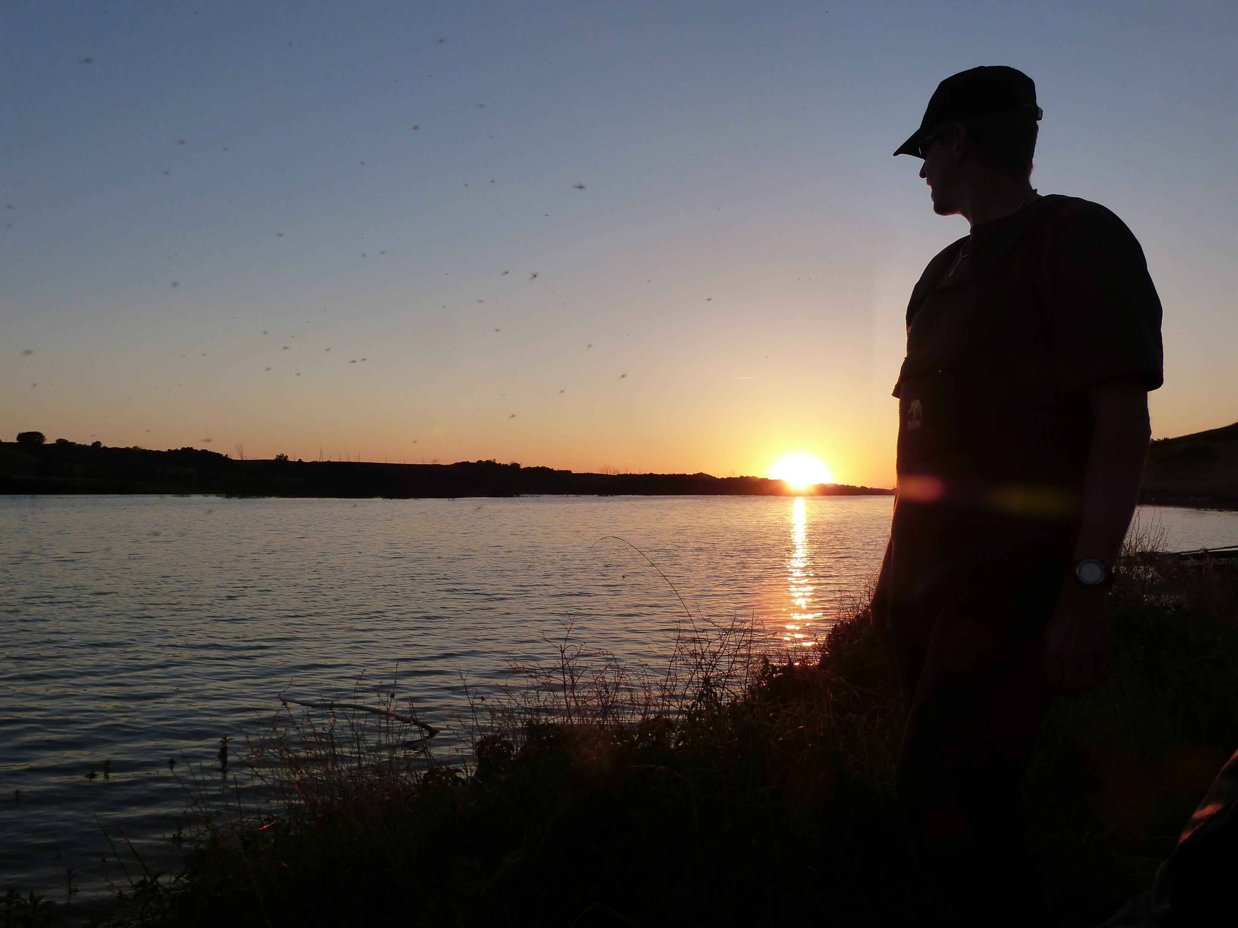 Bivvy Session: Karpfenangeln Frankreich Angler genießen einen ruhigen Sonnenuntergang am Wasser, perfekt zum Karpfenangeln.