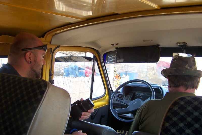 Gelber-Blitz-3 Zwei Angler diskutieren in einem gelben Fahrzeug über Angelausrüstung, bereit für einen Ausflug.