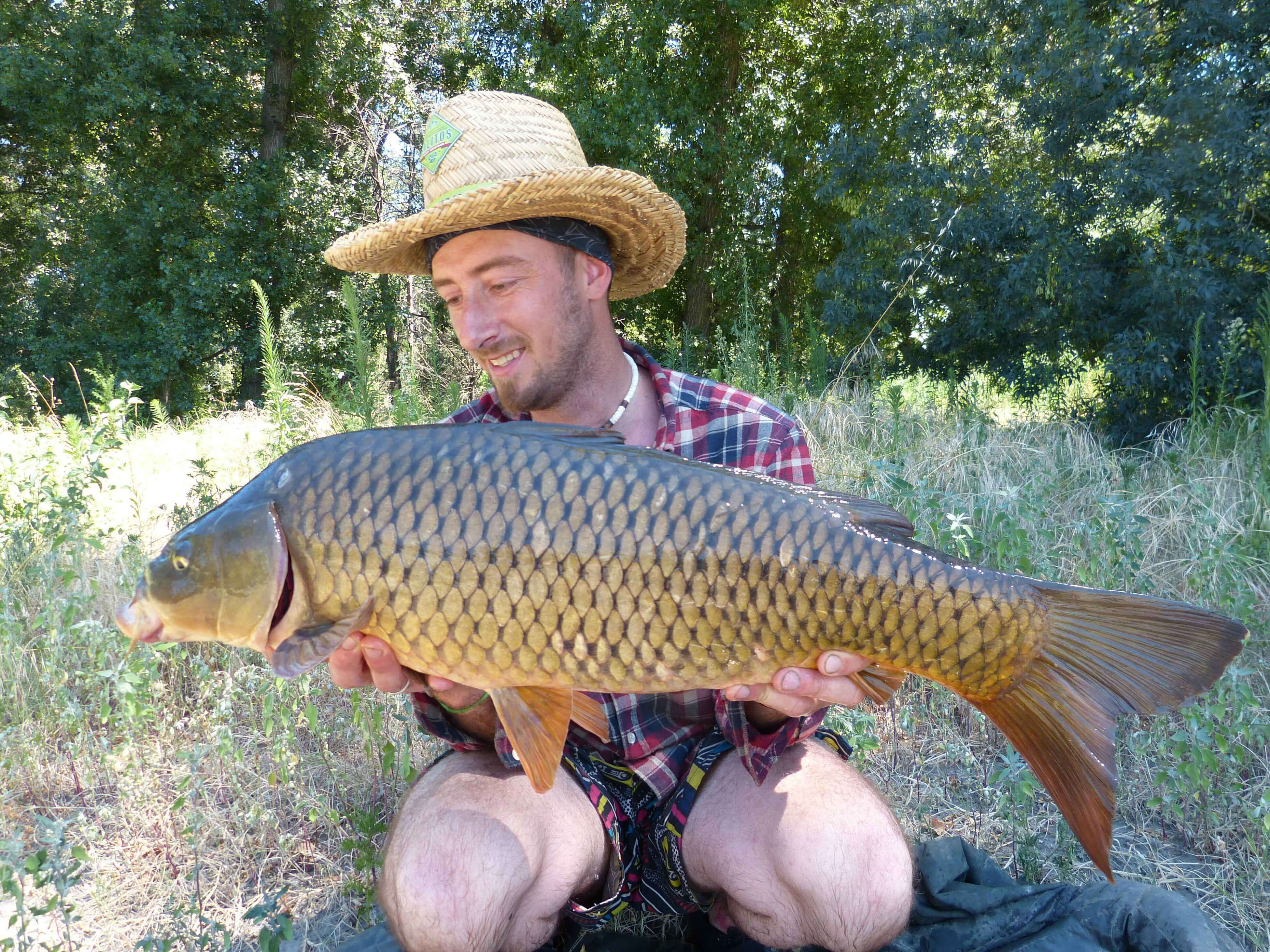 karpfenangeln_frankreich_107 Angler hält stolz einen großen Karpfen und präsentiert erfolgreiche Angeltechniken und Angelgeräte.