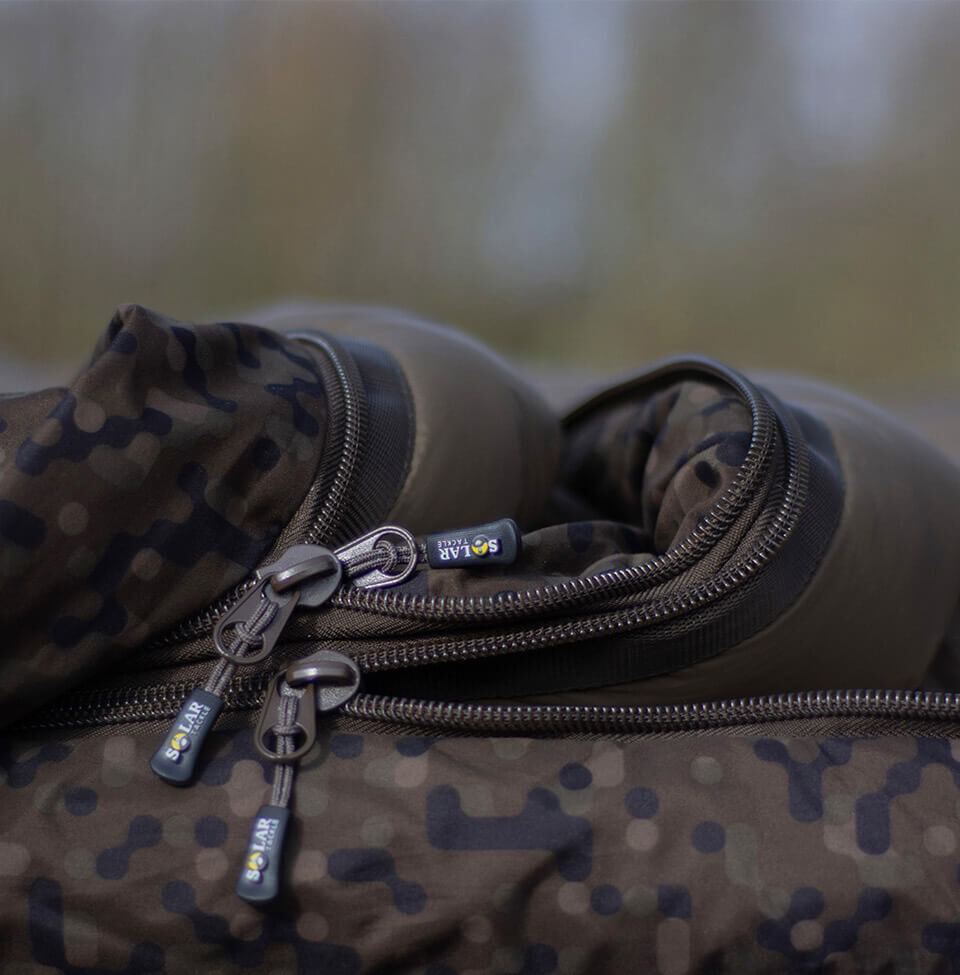 Close-up van Solar Tackle slaapzakritsen met camouflagepatroon voor karpervistuig.