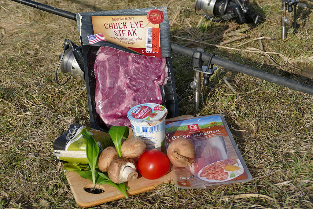 lecker-essen-beim-angeln Frische Zutaten für eine Angelausflugsmahlzeit, darunter Steak, Speck und Gemüse.