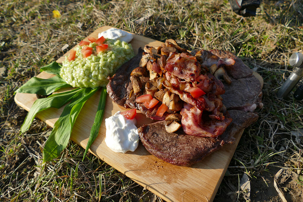 kochen-beim-angeln Köstliches gegrilltes Steak mit Pilzen und frischen Belägen, perfekt für einen Angelausflug.
