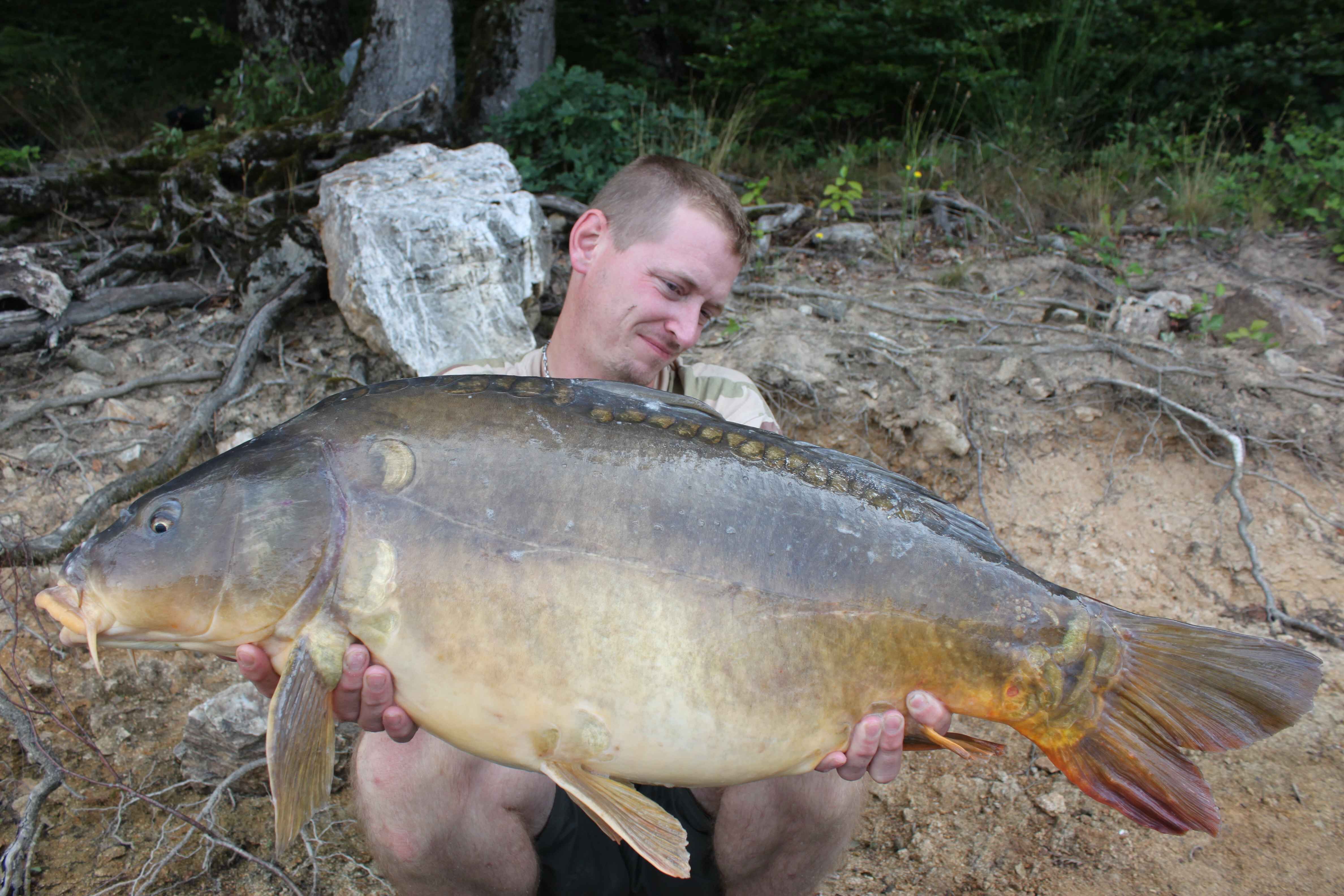 036a Angler hält stolz einen großen Karpfen in der Hand und zeigt damit den Nervenkitzel des erfolgreichen Angelns.