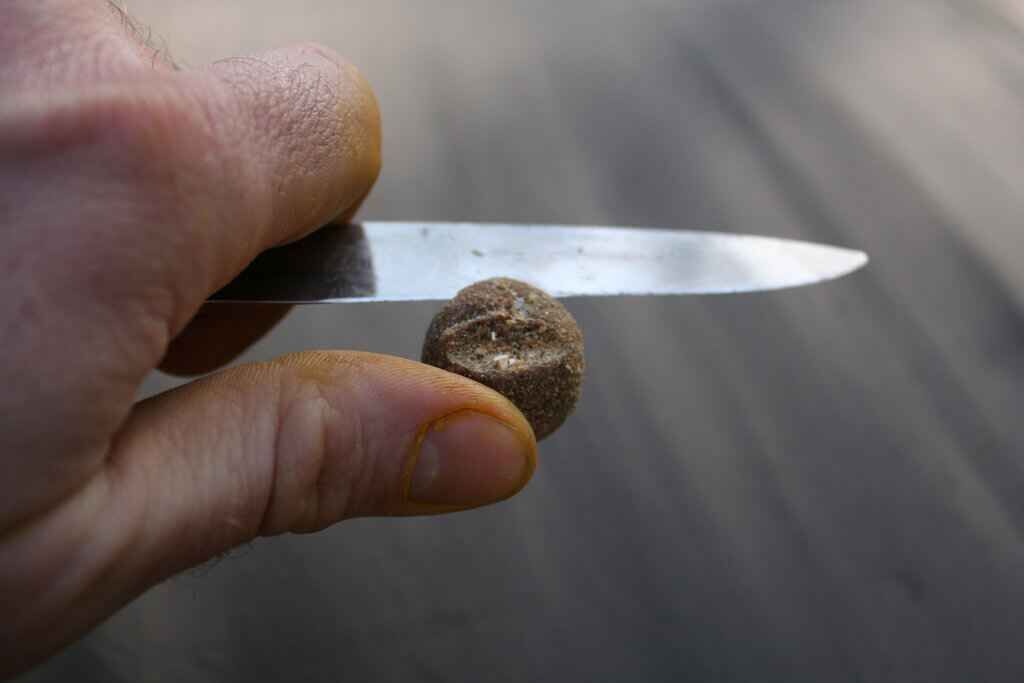 IMG_0339 Ein Angler bereitet mit einem Messer einen Köderball für den Erfolg beim Karpfenangeln vor.