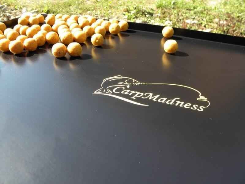 Gigant-Bivvy-Table1 Köderbälle zum Karpfenangeln, verstreut auf einem schwarzen Tablett mit CarpMadness-Logo.