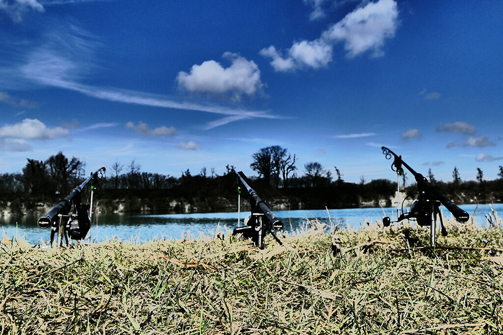 karpfenruten Drei Angelruten an einem ruhigen See, bereit für Abenteuer beim Karpfenangeln.