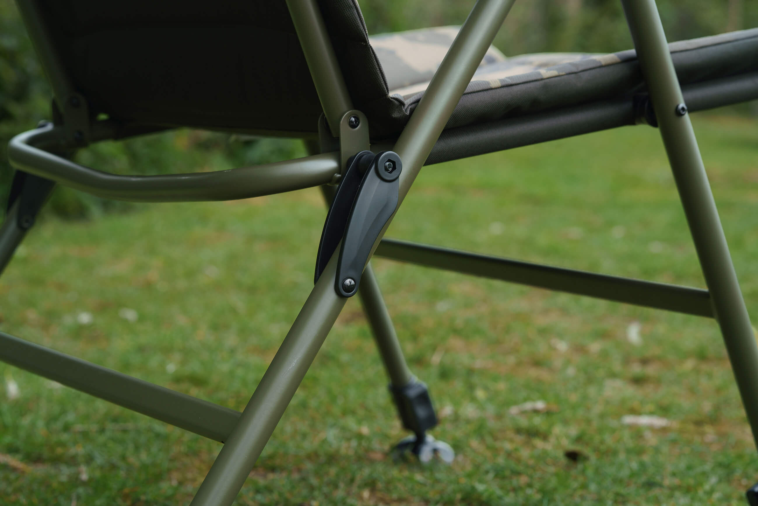 Close-up van een duurzame olijfgroene karpervisstoel met het stevige frame en scharniermechanisme.