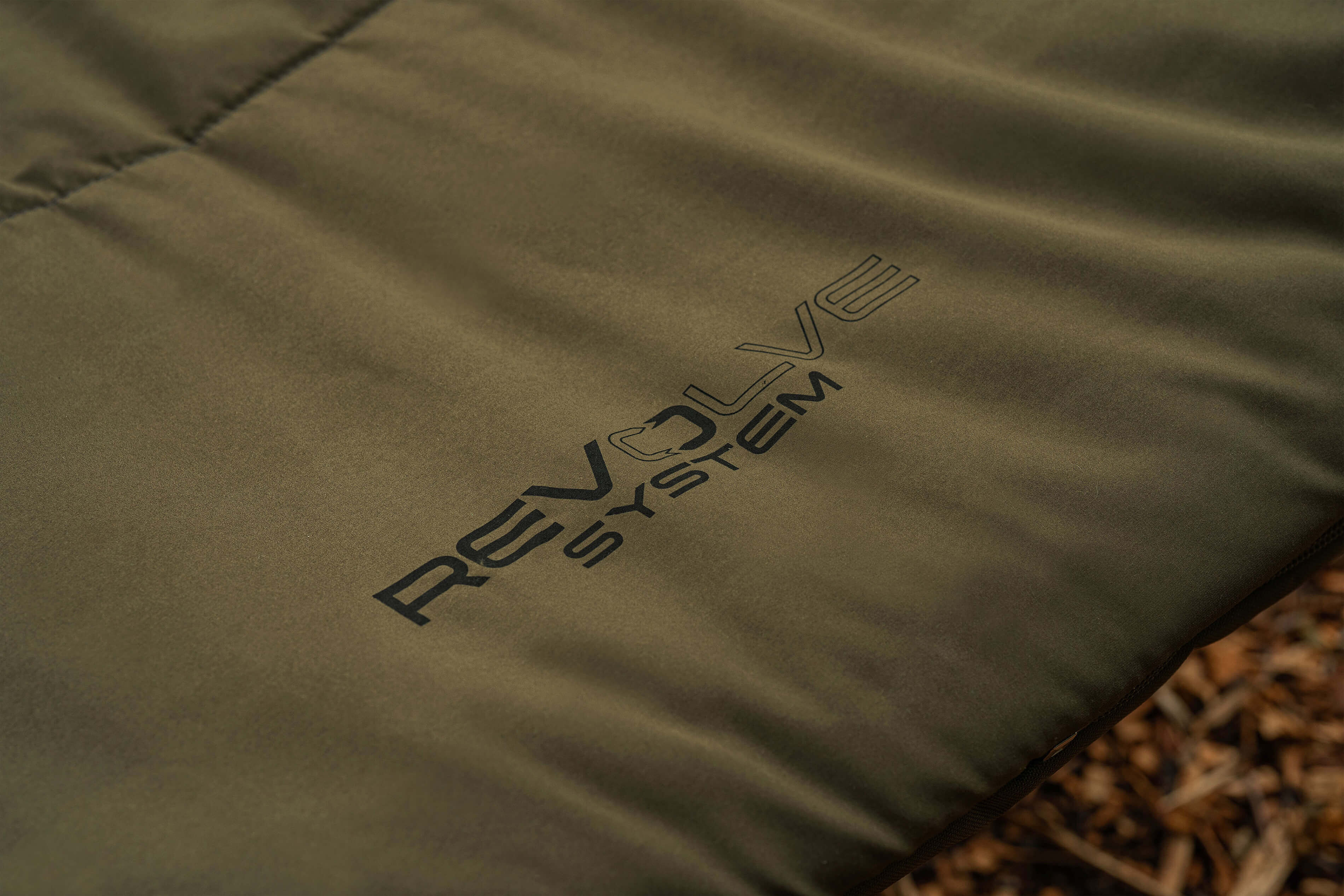 Primer plano de una cómoda silla de pesca con el logotipo de REVOLVE SYSTEM, perfecta para pescadores de carpas.