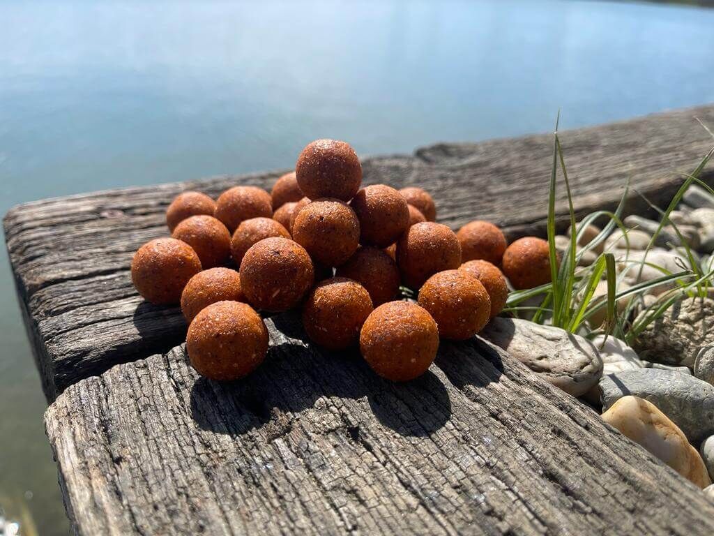 Een stapel hoogwaardige boilies op een houten ondergrond, perfect voor het karpervissen.