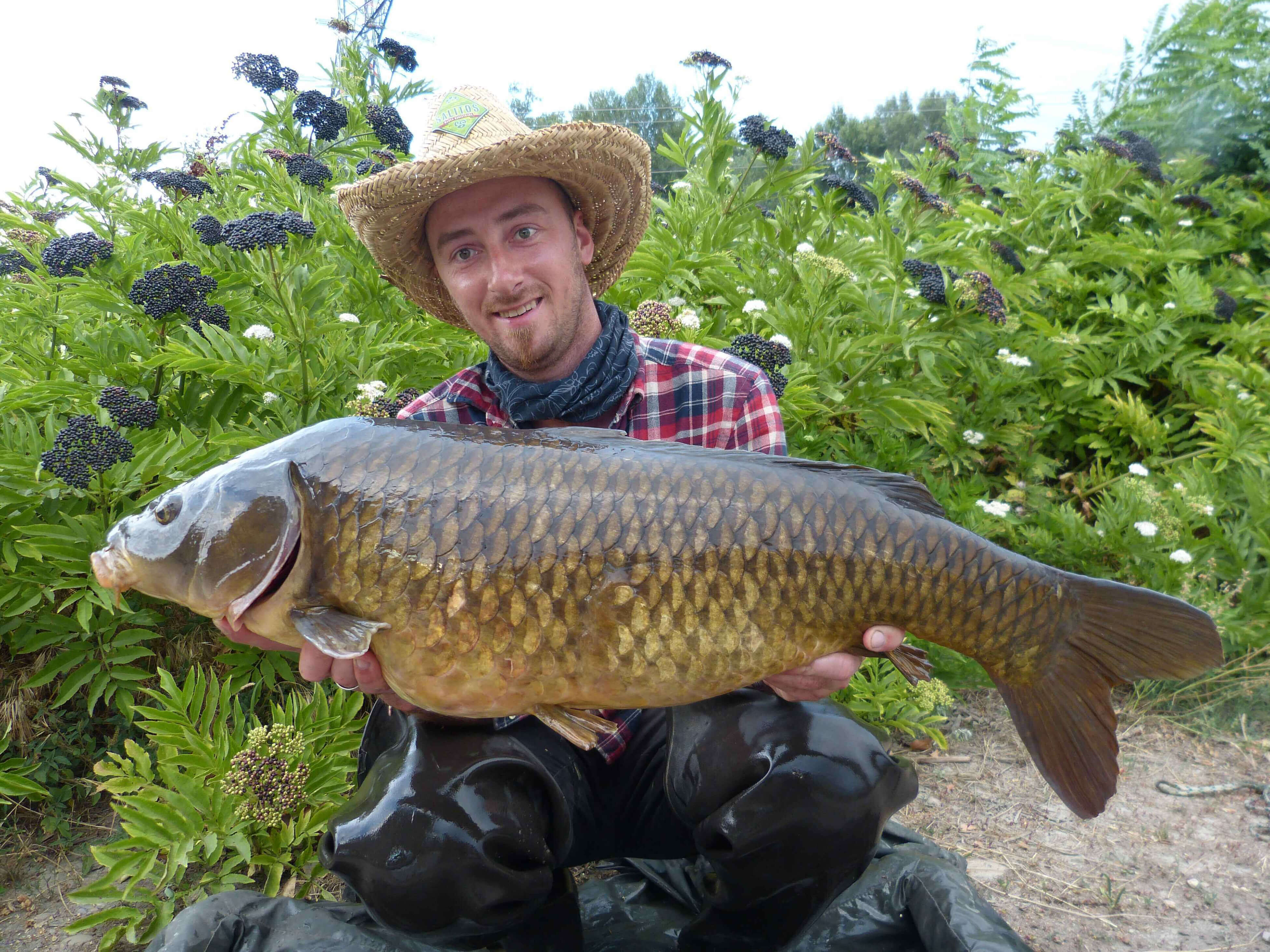 karpfenangeln_frankreich_087 Angler hält stolz einen großen Karpfen und präsentiert erfolgreiche Angeltechniken und Ausrüstung.