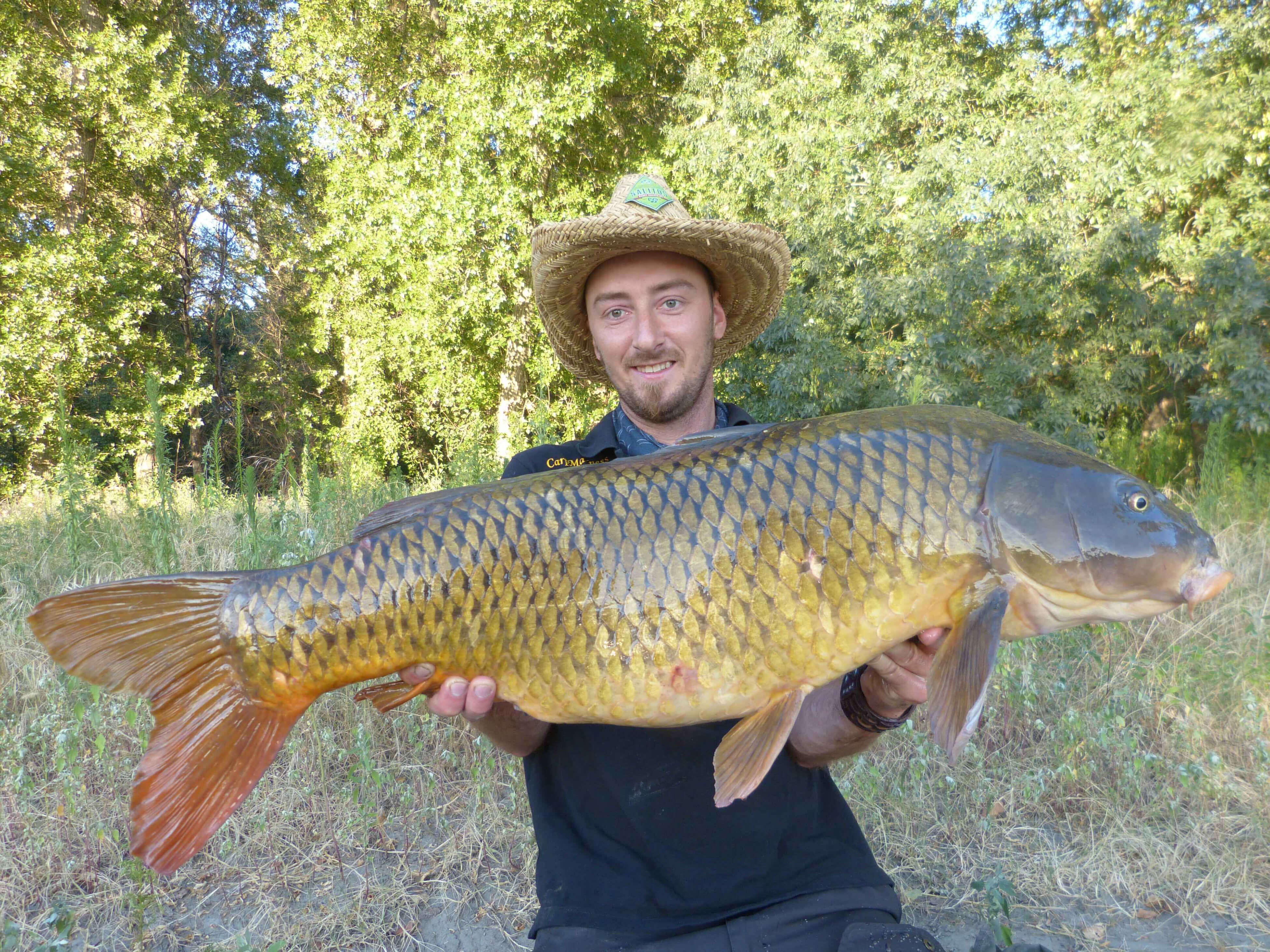 karpfenangeln_frankreich_143 Angler hält stolz einen großen Karpfen in der Hand, der mit hochwertigem Angelgerät gefangen wurde.