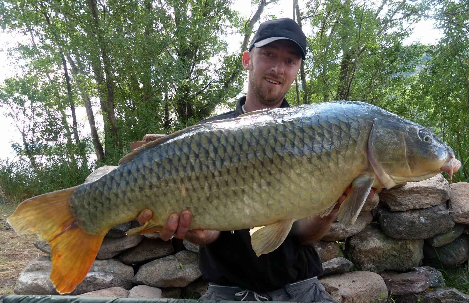 FrankreichtourmitJan234 Ein stolzer Angler, der einen großen Karpfen in der Hand hält und sein erfolgreiches Karpfenangeln unter Beweis stellt.