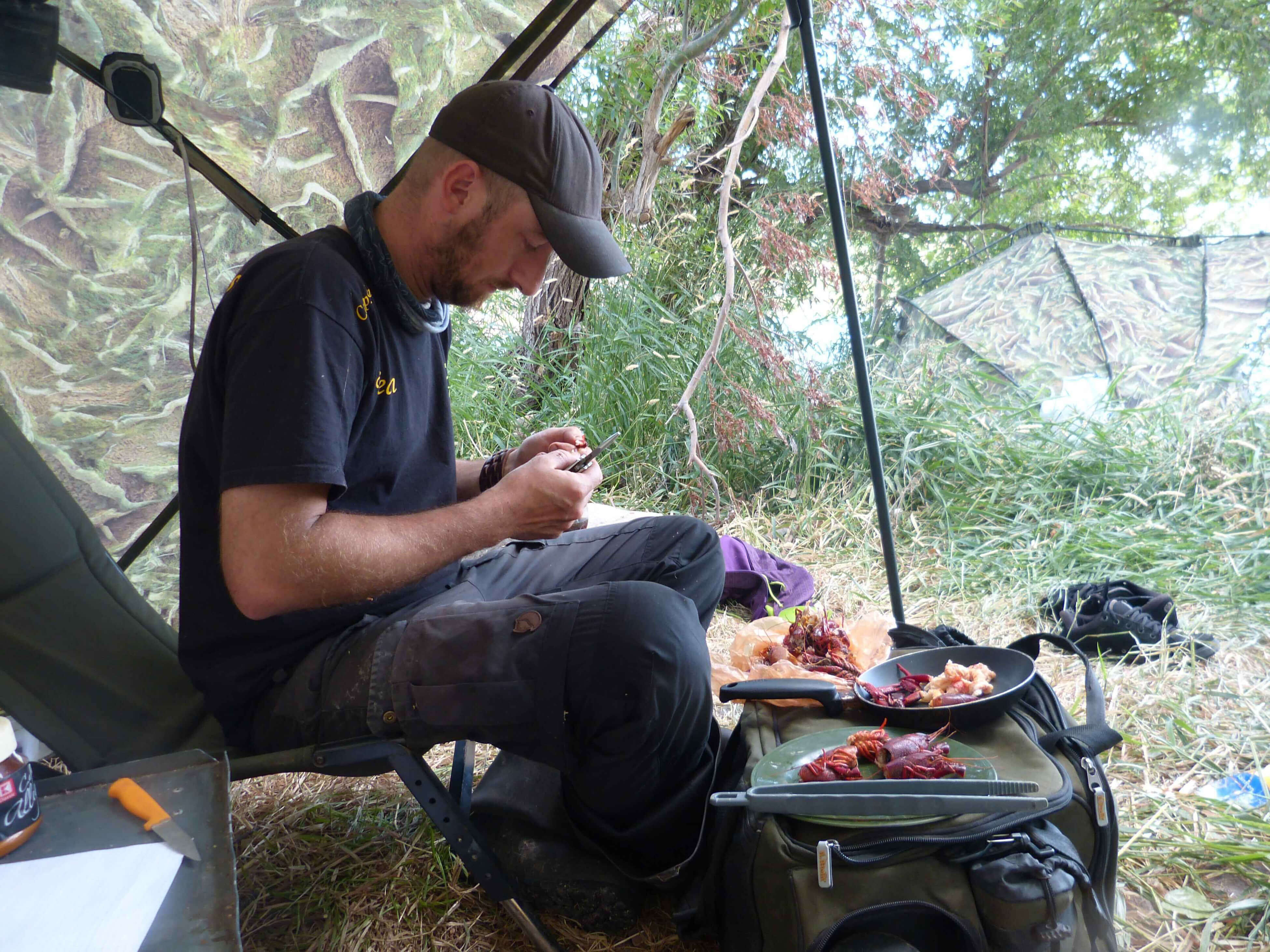 karpfenangeln_frankreich_203 Angler bereitet Köder in einem Angelzelt mit Angelgerät und Futter vor.