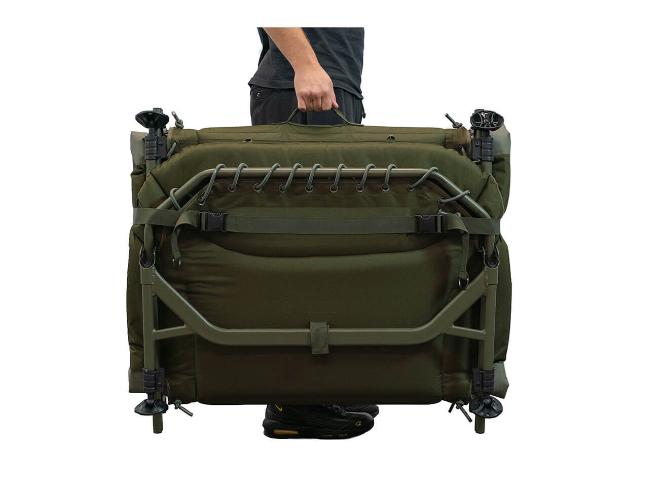 Un pêcheur portant un bedchair de pêche à la carpe vert olive plié avec une structure en métal robuste.