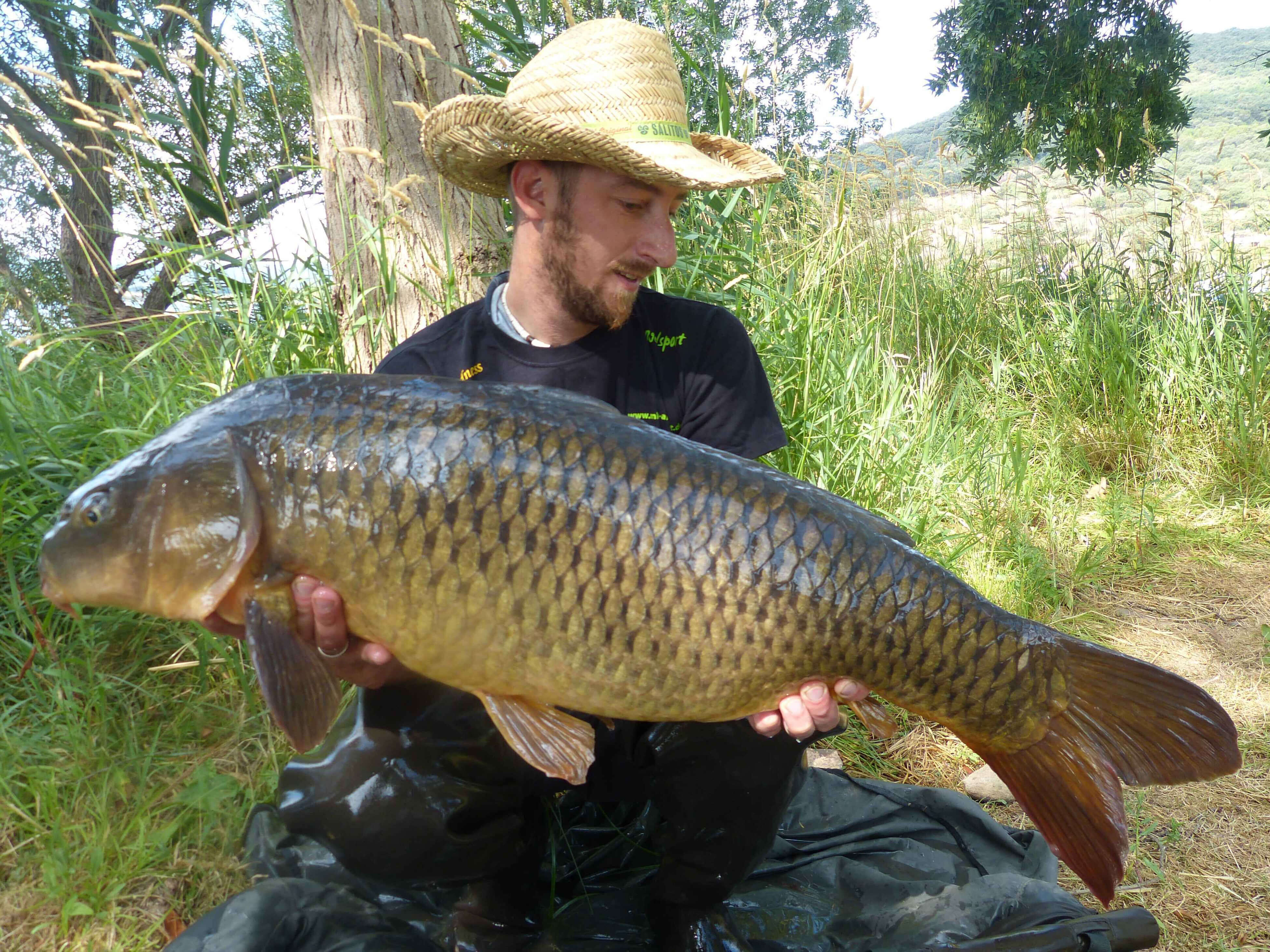 karpfenangeln_frankreich_278 Angler hält stolz einen großen Karpfen und präsentiert erfolgreiche Angeltechniken und Angelgeräte.