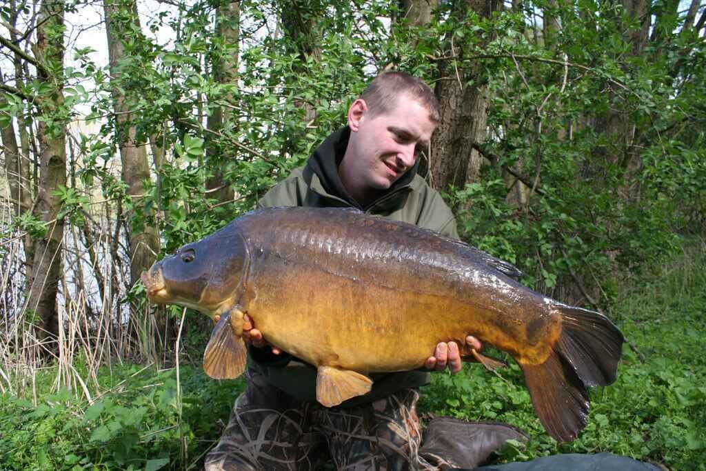Karpfenangeln für Kurzentschlossene Angler hält stolz einen großen Karpfen und präsentiert erfolgreiche Angeltechniken und Ausrüstung.