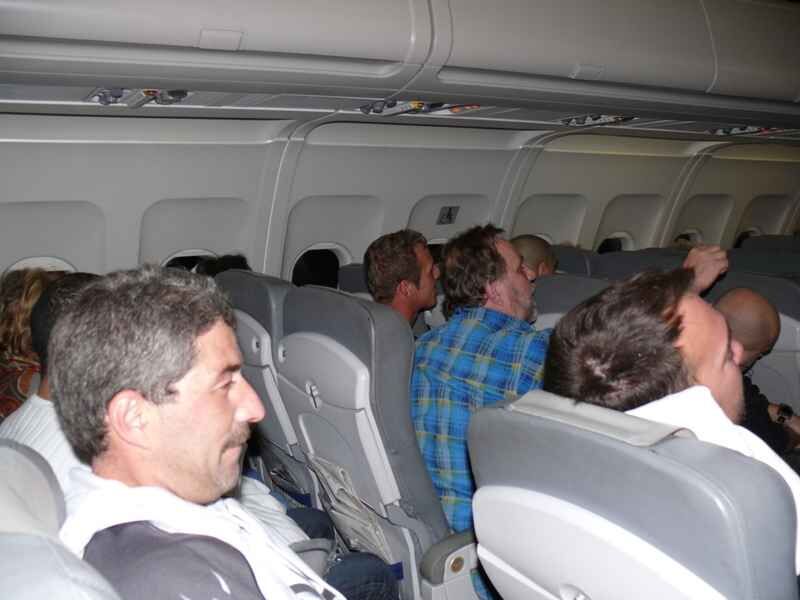 R-ckflug-2 Gruppe von Anglern bespricht Angelausrüstung und -techniken im Flugzeug zu einem Angelziel.
